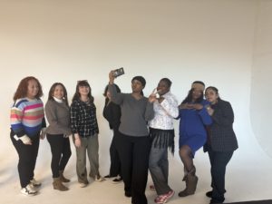 A group of ladies behind a white background. 